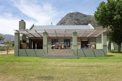 a house with a mountain in the background at Jardin de la Ferme in Franschhoek