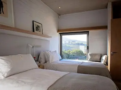 two beds in a room with a large window at Stonehaven Eco Cabins in Hermanus