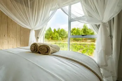a bedroom with a white bed with a window at Stonehaven Eco Cabins in Hermanus