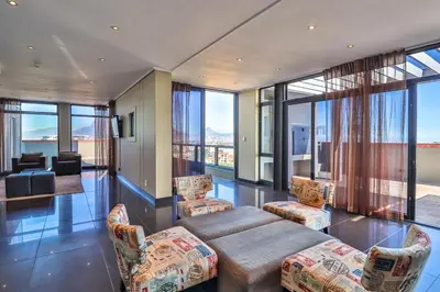 a living room with a couch and chairs and windows at Manhattan Towers 506 by CTHA in Cape Town