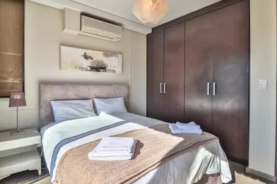 a bedroom with a large bed with brown cabinets at Manhattan Towers 506 by CTHA in Cape Town