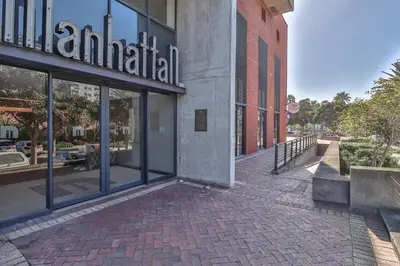 a building with glass windows on a brick sidewalk at Manhattan Towers 506 by CTHA in Cape Town