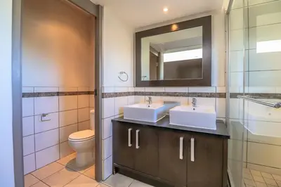 a bathroom with two sinks and a toilet and a mirror at Manhattan Towers 506 by CTHA in Cape Town