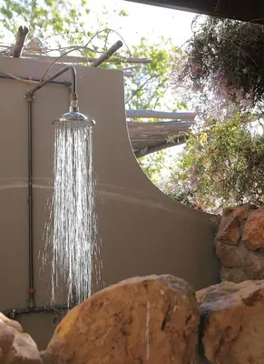 a shower hanging from a wall next to a rock at Porcupine Hills Olive and Guest Farm in Botrivier