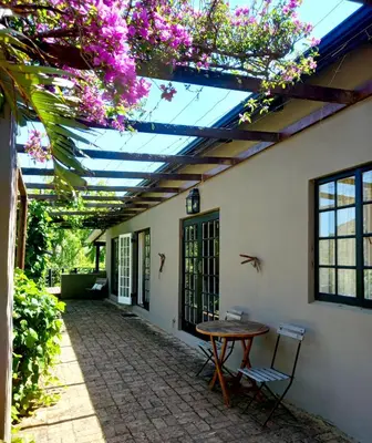 a patio with a table and chairs and flowers at Porcupine Hills Olive and Guest Farm in Botrivier