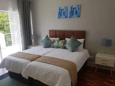 a bedroom with a large bed with white sheets and pillows at Prestigious Guest Villa in Cape Town