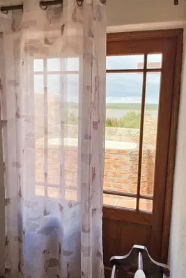 a window with a curtain and a chair in a room at Lagoon View in Hermanus in Hermanus