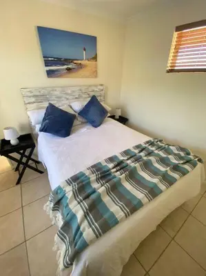 a bedroom with a bed with blue pillows and a lighthouse at Hermanus Beach Club 31 in Hermanus