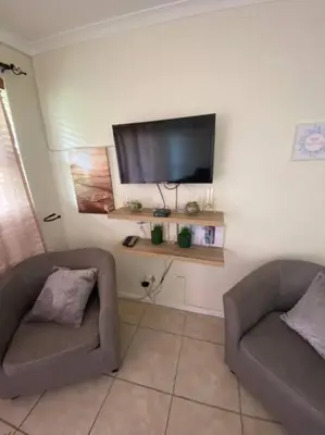 a living room with two chairs and a flat screen tv at Hermanus Beach Club 31 in Hermanus
