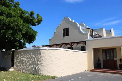 a white house with a fence in front of it at Classic Cape Dutch Studio Apartment in Cape Town