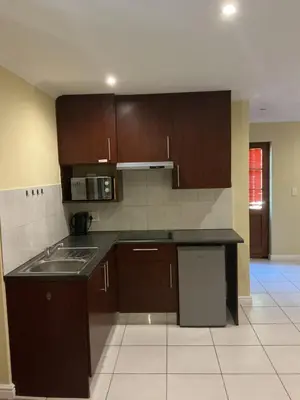 an empty kitchen with brown cabinets and a sink at Classic Cape Dutch Studio Apartment in Cape Town