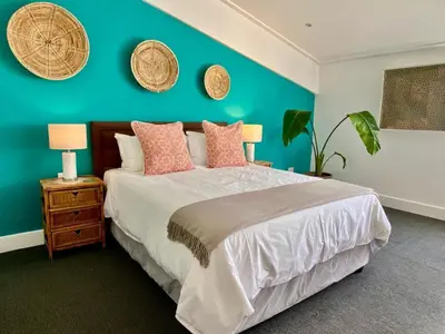 a bedroom with a bed and a blue wall at Hermanus Waterfront Apartment in Hermanus