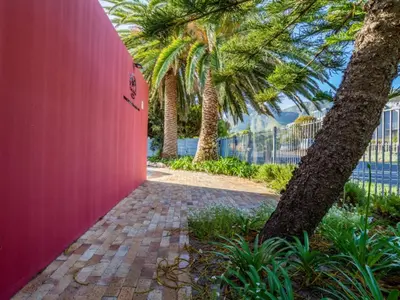 a pink wall with palm trees and a sidewalk at Two Palm House - Vermont Hermanus in Hermanus
