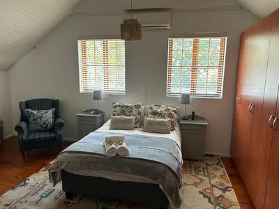 a bedroom with a bed and a chair and windows at Paradyskloof Suite in Stellenbosch