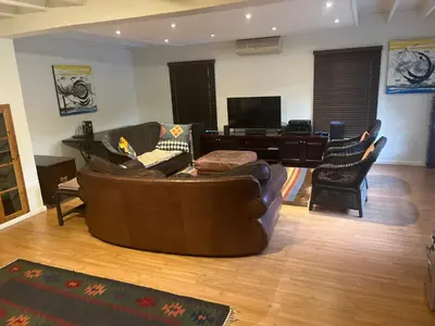 a living room with a leather couch and a piano at Paradyskloof Suite in Stellenbosch