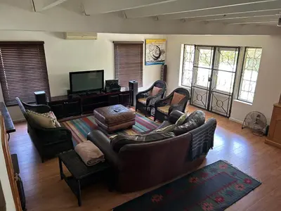 a living room with leather furniture and a flat screen tv at Paradyskloof Suite in Stellenbosch