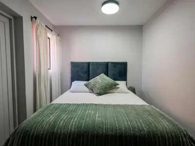 a bedroom with a large bed with a green blanket at iMoyo Ocean Villa and Studio, Hermanus in Hermanus