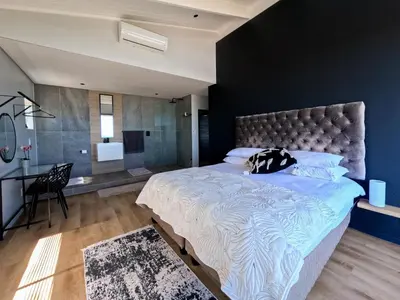 a bedroom with a large bed and a desk at iMoyo Ocean Villa and Studio, Hermanus in Hermanus