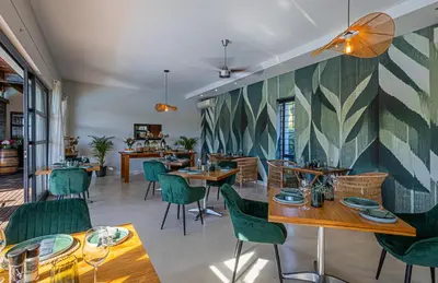 a restaurant with wooden tables and green chairs at Ladybird Boutique Hotel at Kanonkop in Stellenbosch