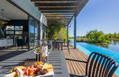 a table with a plate of food next to a swimming pool at Ladybird Boutique Hotel at Kanonkop in Stellenbosch