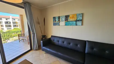 a black couch in a living room with a balcony at La Palmera - Island Club Canal Front in Cape Town
