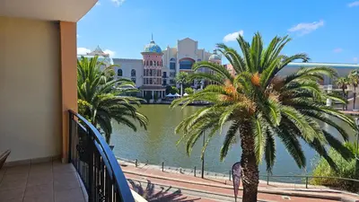 a balcony with a palm tree and a body of water at La Palmera - Island Club Canal Front in Cape Town