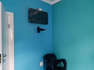 a blue room with a chair and a tv on a wall at Hasate Guest House ,4 st james street Oakdale Belliville Cape Town South Africa in Cape Town