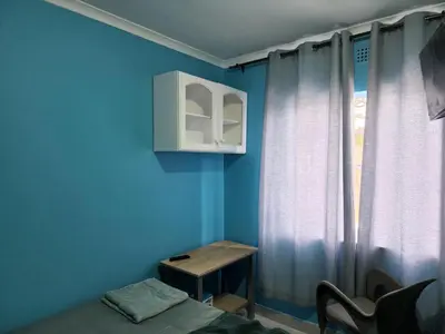 a blue room with a small table and a window at Hasate Guest House ,4 st james street Oakdale Belliville Cape Town South Africa in Cape Town