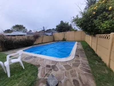 a swimming pool with a white chair next to a fence at Zenith House Boston Self Catering Accomodation in Cape Town