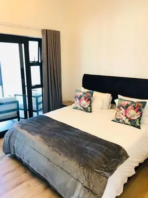 a bedroom with a large bed with two pillows at Glow Boutique Suites & Guesthouse in Hermanus