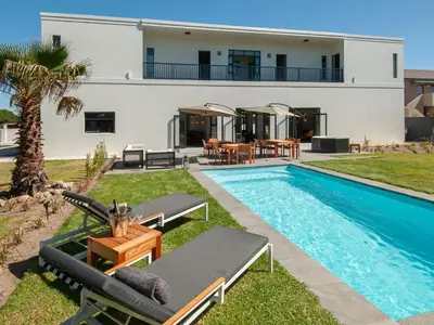 a villa with a swimming pool and a house at Glow Boutique Suites & Guesthouse in Hermanus