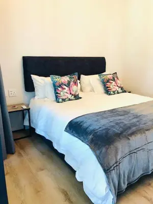 a bedroom with a large bed with two pillows at Glow Boutique Suites & Guesthouse in Hermanus