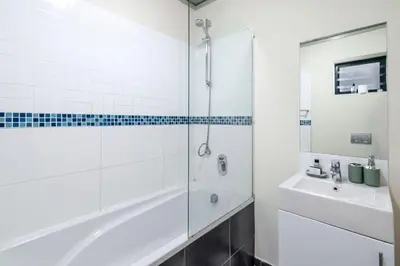 a bathroom with a shower and a tub and a sink at 2 Bedroom Secure Pool Strong WiFi in Cape Town