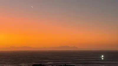a sunset over the ocean with the moon in the sky at The Butterfly Villa in Pringle Bay