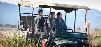 three people standing in a golf cart in a field at Wild Olive House at Bartholomeus Klip in Hermon
