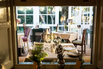 a dining room with a table and chairs and a window at Wild Olive House at Bartholomeus Klip in Hermon