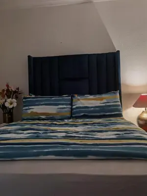 a blue bed with a black headboard and pillows at Galaxy Sleep And Go Rooms Goodwood in Cape Town