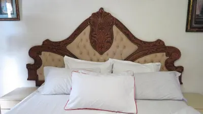 a bed with a wooden headboard and white pillows at Galaxy Sleep And Go Rooms Goodwood in Cape Town