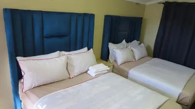 two beds in a room with blue curtains at Galaxy Sleep And Go Rooms Goodwood in Cape Town