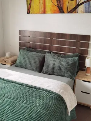 a bedroom with a bed with a wooden headboard at Galaxy Sleep And Go Rooms Goodwood in Cape Town
