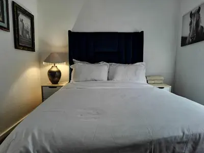 a bedroom with a large white bed with a blue headboard at Galaxy Sleep And Go Rooms Goodwood in Cape Town