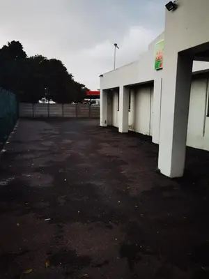 an empty parking lot next to a white building at Galaxy Sleep And Go Rooms Goodwood in Cape Town