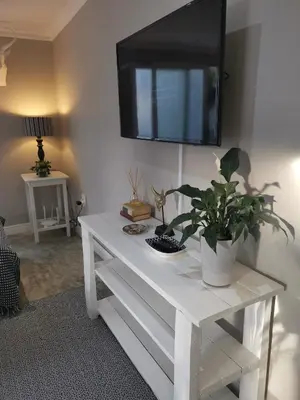 a white console table with a tv on a wall at Gray Cottage in Strand