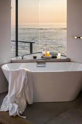 a bath tub with a view of the ocean at OnTheRocksBB Solar Powered Guesthouse and Ocean Lodge in Bettyʼs Bay
