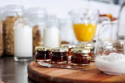 a wooden cutting board with jars of honey on a table at OnTheRocksBB Solar Powered Guesthouse and Ocean Lodge in Bettyʼs Bay