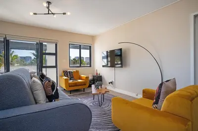 a living room with two couches and a tv at Knightsbridge Terrace in Cape Town