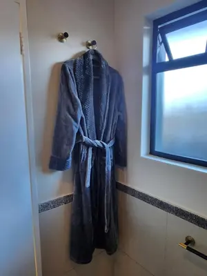 a blue robe hanging on a wall next to a window at Knightsbridge Terrace in Cape Town