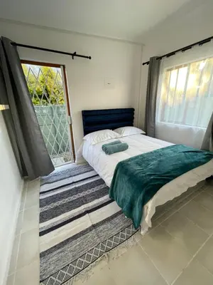 a bedroom with a bed and a large window at Cub's Home in Cape Town
