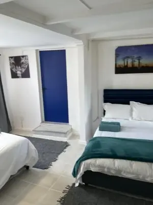 a bedroom with two beds and a blue window at Cub's Home in Cape Town
