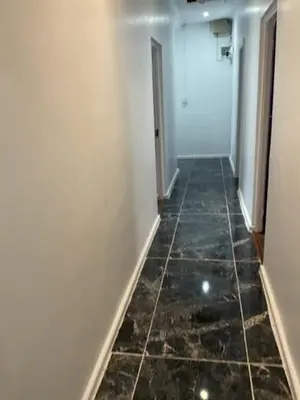 a hallway with a tile floor and a white wall at Cub's Home in Cape Town